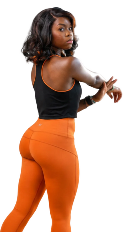 Woman wearing black top and orange leggings on a white background