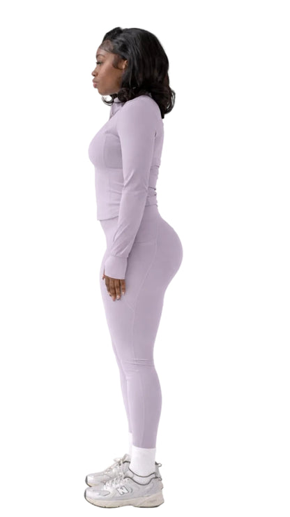 Woman wearing a light gray long-sleeve top and leggings on a white background