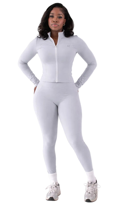 Woman wearing a light gray athletic outfit on a white background